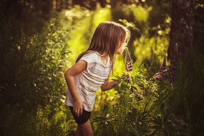 My little girl is smelling flowel in sunny pre-sunset beautiful woods. 