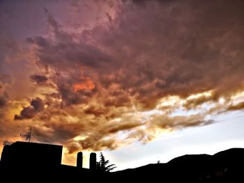 Low angle view of silhouette buildings against dramatic sky