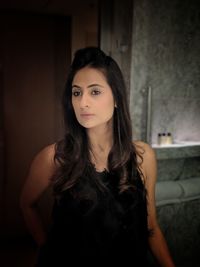 Portrait of beautiful young woman standing against wall