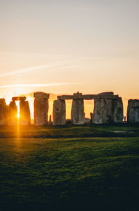 Built structure on landscape against sky during sunset