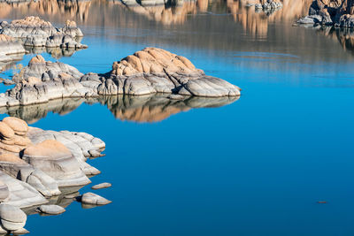 Reflection of rocks in lake against blue sky