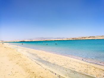 Scenic view of beach against clear blue sky