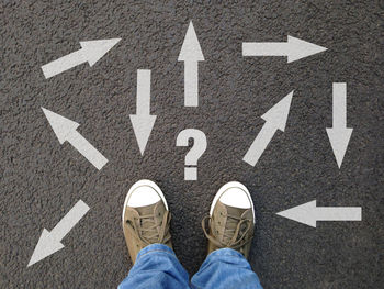 Low section of man standing on road sign