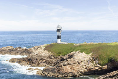 Lighthouse by sea against sky