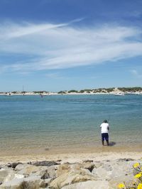 Rear view of man on beach against sky