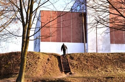 Rear view of man moving up on steps against building