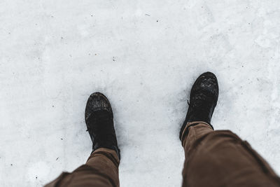 Low section of man standing on snow covered land