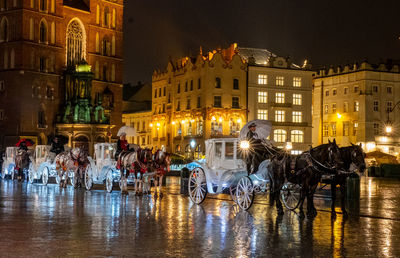 People on illuminated street amidst buildings at night