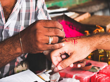 Midsection of man painting on customer hand