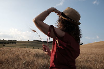 Woman wearing sun hat while standing in wheat field against sky