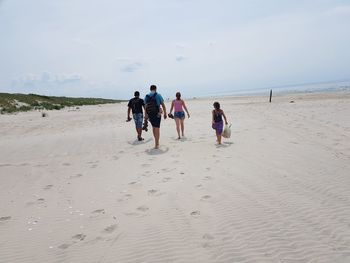 Group of people walking on sand at beach