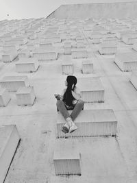 Full length of woman sitting on staircase against building