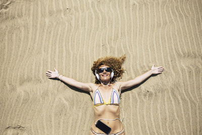 Directly above shot of woman in bikini lying on sand at beach