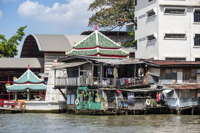 Buildings by river against sky