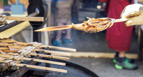 Grilled fish skewers being cooked at an outdoor market, barbeque, street food stall