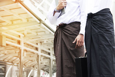 Midsection of business people in lungi standing by building