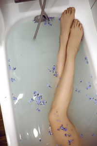Woman is lying in the bath with water in the spa and small blue forget-me-nots