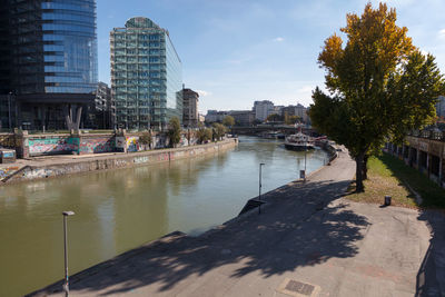 River by buildings in city against sky