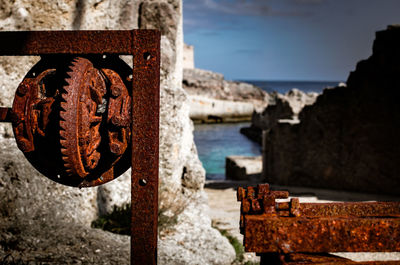 Close-up of rusty metal by sea against sky