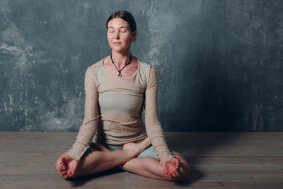 Woman meditating against wall