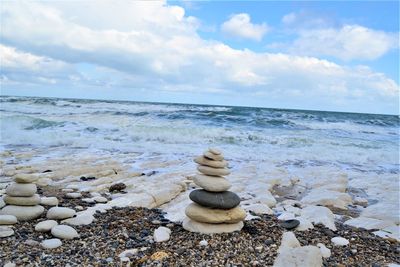 Stack of stones on beach against sky