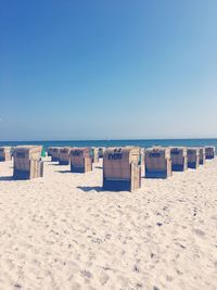 Hooded chairs on beach against clear sky