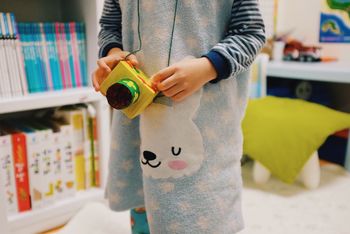 Midsection of child holding toy camera at home