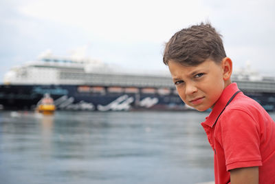 Portrait of boy standing in water against sky