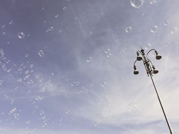 Low angle view of street light against sky and soap balls