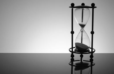 Close-up of hourglass on table against gray background