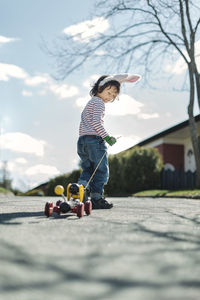 Full length of boy pulling toy car on footpath at yard