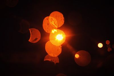 Close-up of illuminated lights against sky at night