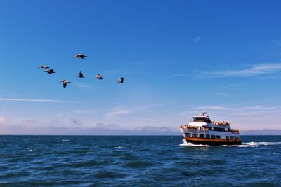 Boat sailing in sea against blue sky