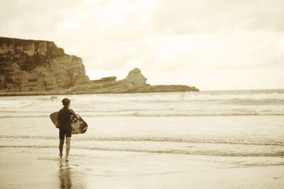 Rear view of man standing on beach against sky