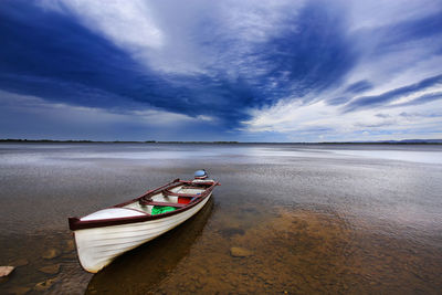 Boat moored on beach against sky