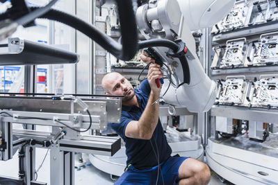 Man working at industrial robot in modern factory