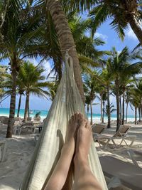 Low section of man relaxing on hammock at beach