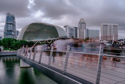 Bridge over river by buildings against sky in city