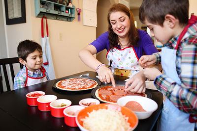 Woman and children making pizza at home