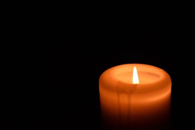 Close-up of illuminated candle over black background