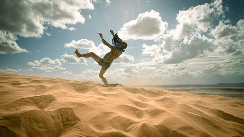 Man jumping in desert against sky