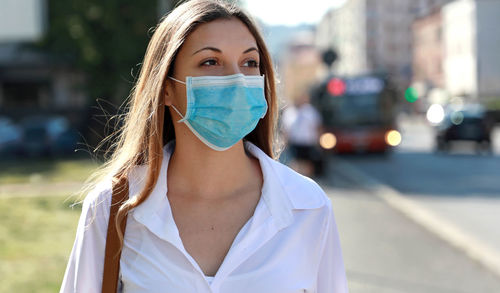 Close-up of young woman wearing face mask phone