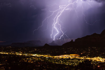 Lightning over illuminated cityscape at night