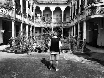 Rear view of woman standing on street amidst buildings