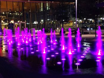 Illuminated fountain by street at night