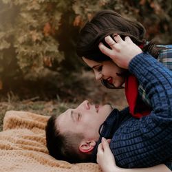 Side view of couple embracing against trees