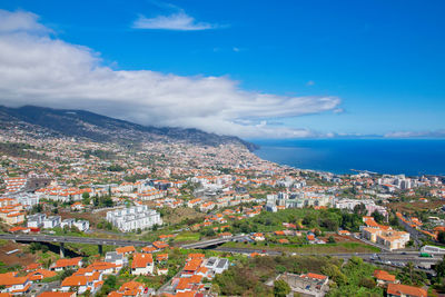 High angle view of townscape by sea against blue sky