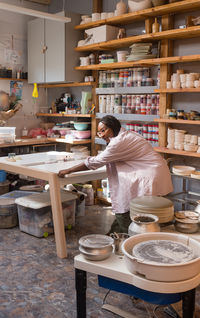 Woman with braided hair at her home art ceramics studio moving table