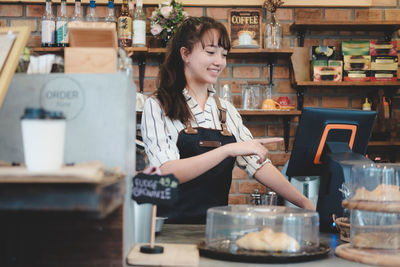 Barista smiling while using computer in cafe