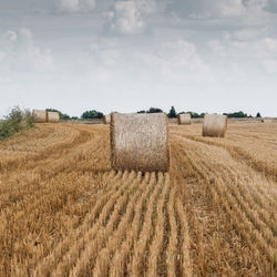 Hay bales on field against sky